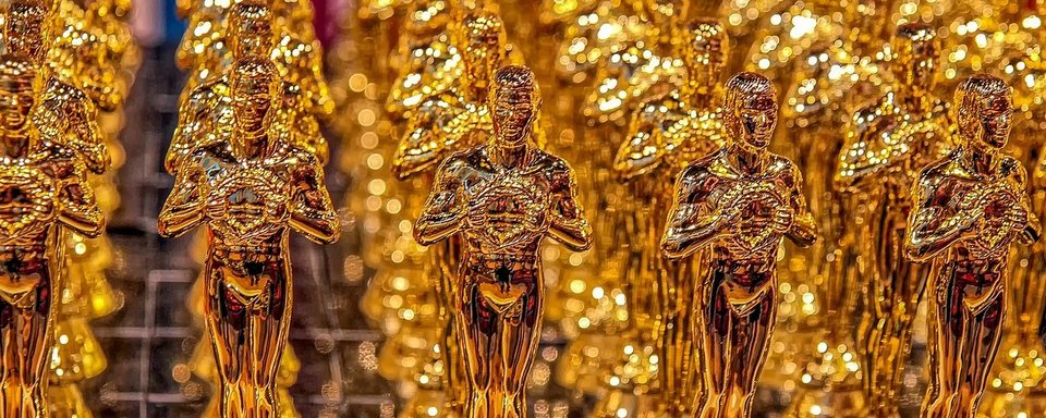 Mehrere goldene Oscar-Statuetten in einer Reihe, symbolisieren Filmpreisverleihung